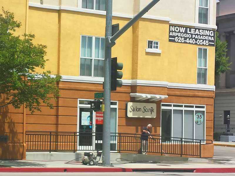 A worker for an apartment complex in Pasadena washes the walls and pavement, April 30, 2015 (Photo - Staff).